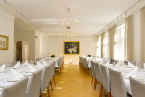 Juhlatila, jossa on kaksi katettua pitkää pöytää.