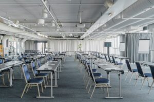 Kokoustila, jossa on paljon tuoleja ja pöytiä.